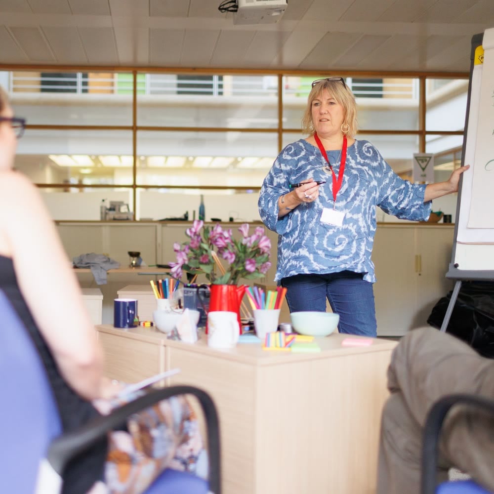 A presenter at a flip chart leading a workshop for a small group